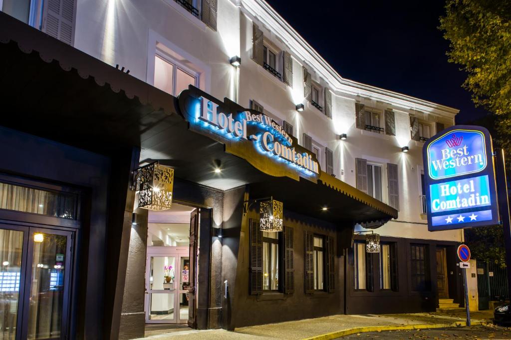 a building with neon signs on the side of it at Best Western Le Comtadin in Carpentras