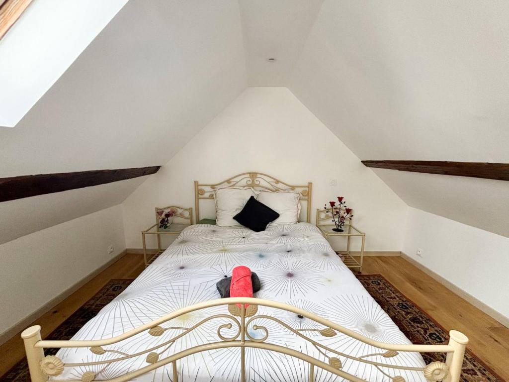 ein Schlafzimmer mit einem weißen Bett mit einem roten Schuh darauf in der Unterkunft Maison à la campagne pour 7 pers, wifi et parking in Aube-sur-Rîle