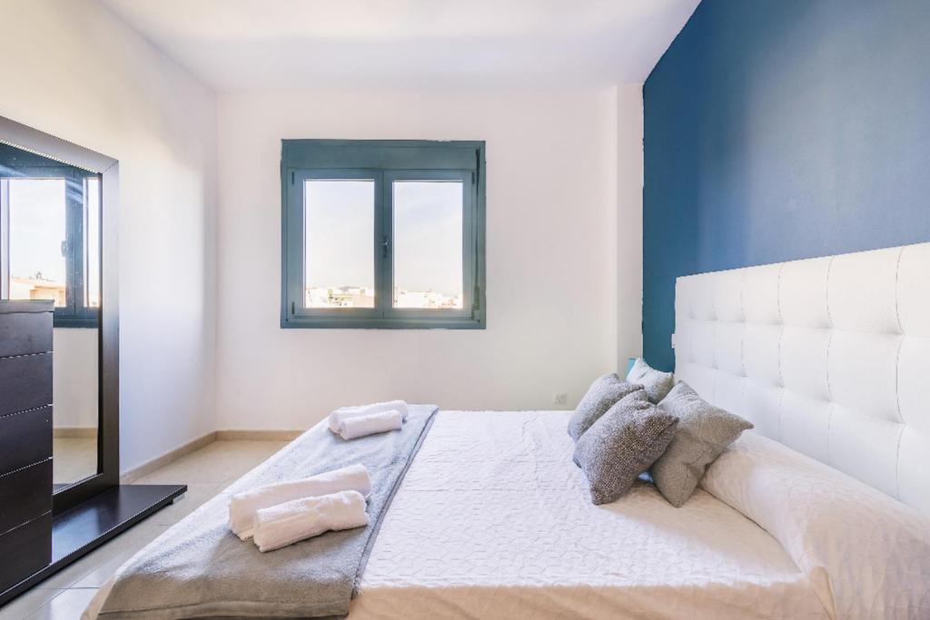 Un dormitorio con una gran cama blanca con ventana. en Blue & White House, en Vecindario
