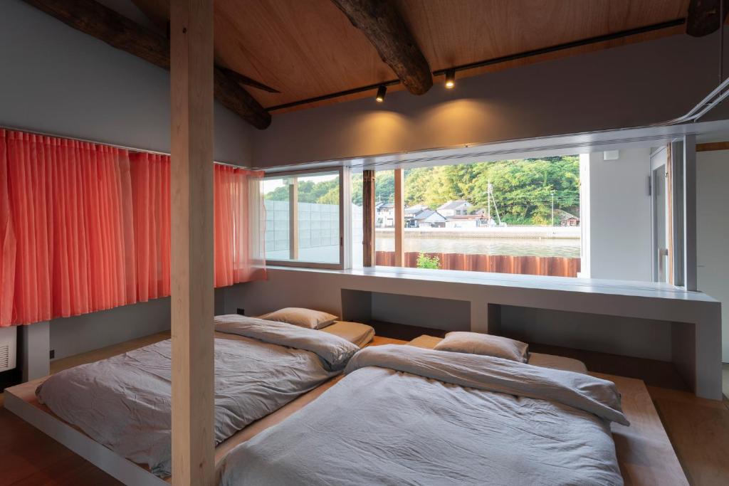 zwei Betten in einem Zimmer mit Fenster in der Unterkunft SEW STAY Slow Seam KYOTO MAIZURU in Maizuru