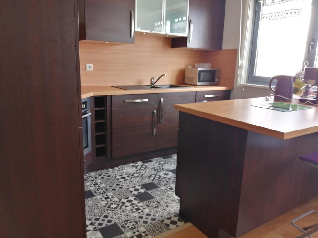 une cuisine avec des armoires en bois et un sol carrelé dans l'établissement AppartMalo, à Saint-Malo