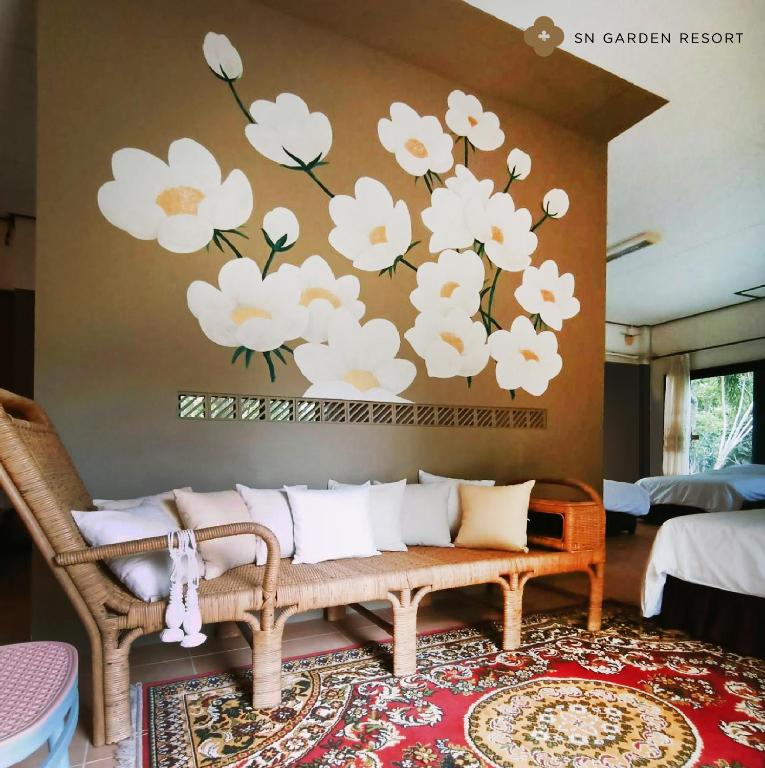 a living room with a couch and flowers on the wall at SN Garden in Ban Bo Hin
