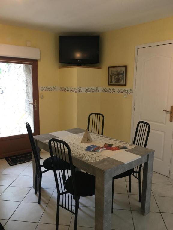 une table à manger avec des chaises et une télévision murale dans l'établissement Épices au cœur du centre ville historique de Serignan, à Sérignan