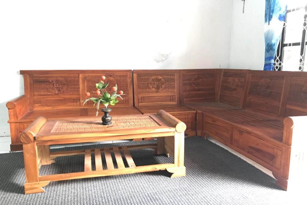 a wooden bench with a table and a vase with flowers at Hotel O Homestay Banyumili Samigaluh in Semigaluh