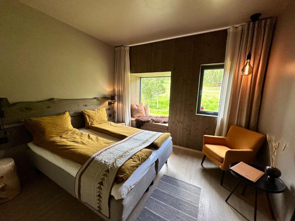 a bedroom with a bed and a chair and a window at Bjørnfjell Mountain Lodge in Alta