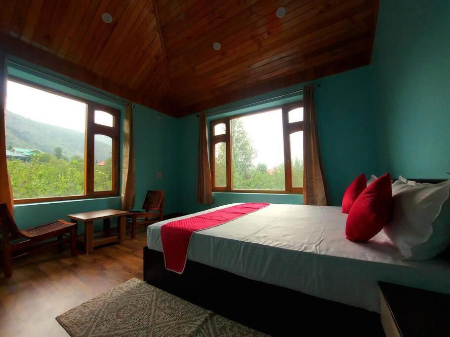 a bedroom with a bed in a room with windows at BnBBuddy Himalayan 3BR Farmstay wid Lawn Near Manali in Manāli