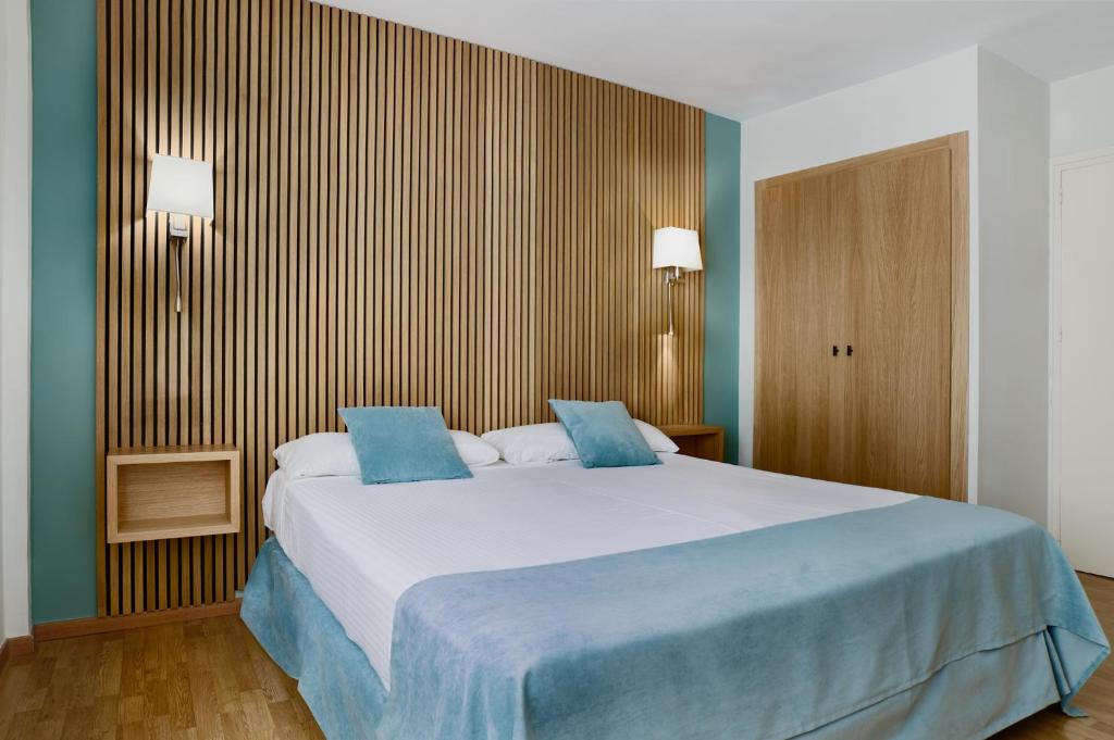 a bedroom with a large bed with blue sheets at Reyes Católicos in Seville