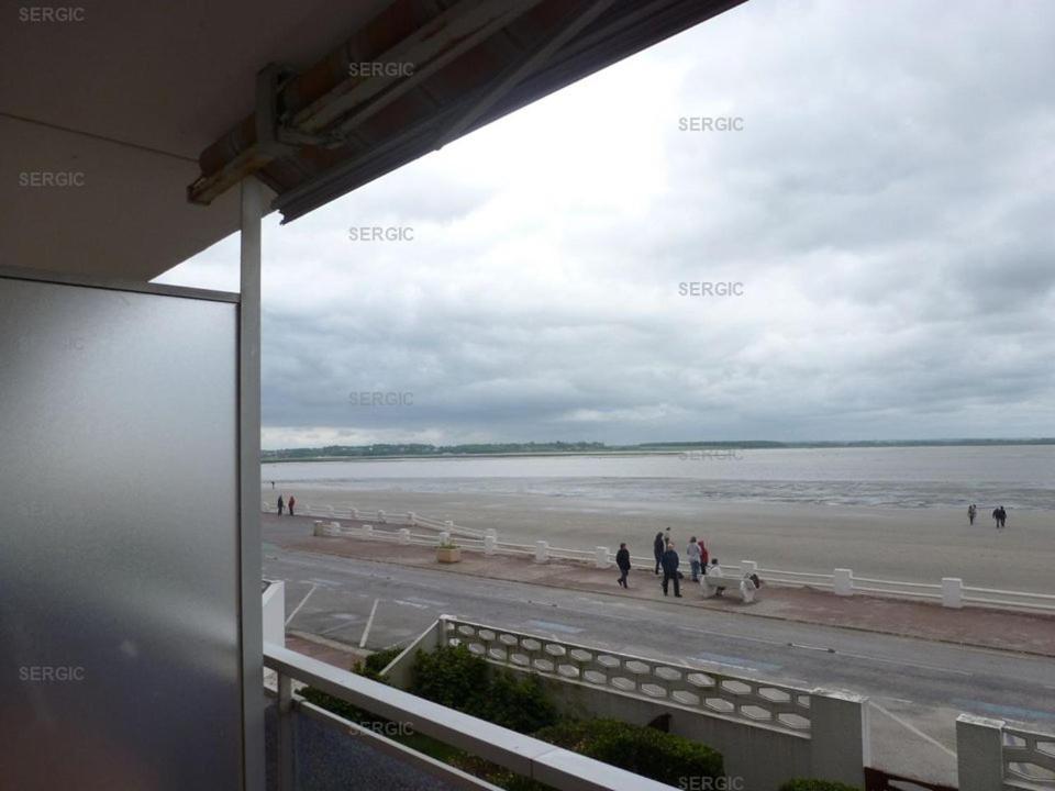 un groupe de personnes marchant sur une plage avec un chien dans l'établissement Annonce de professionnel - Bel appartement, face Mer., au Crotoy