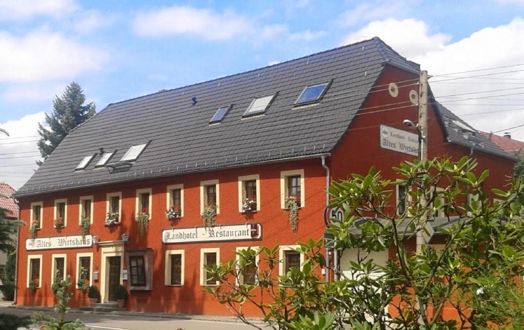 Altes Wirtshaus Fördergersdorf Bed & Breakfast في Tharandt: مبنى احمر كبير بسقف اسود