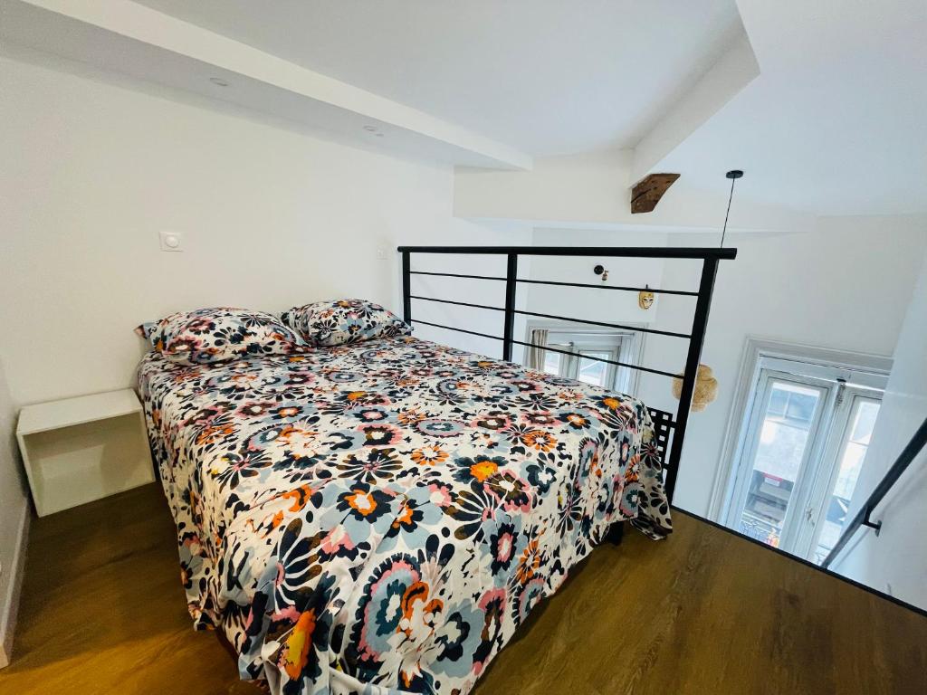 una camera da letto con un letto con un piumone floreale di Magnifique Loft sur 2 niveaux Comédie Gare a Montpellier