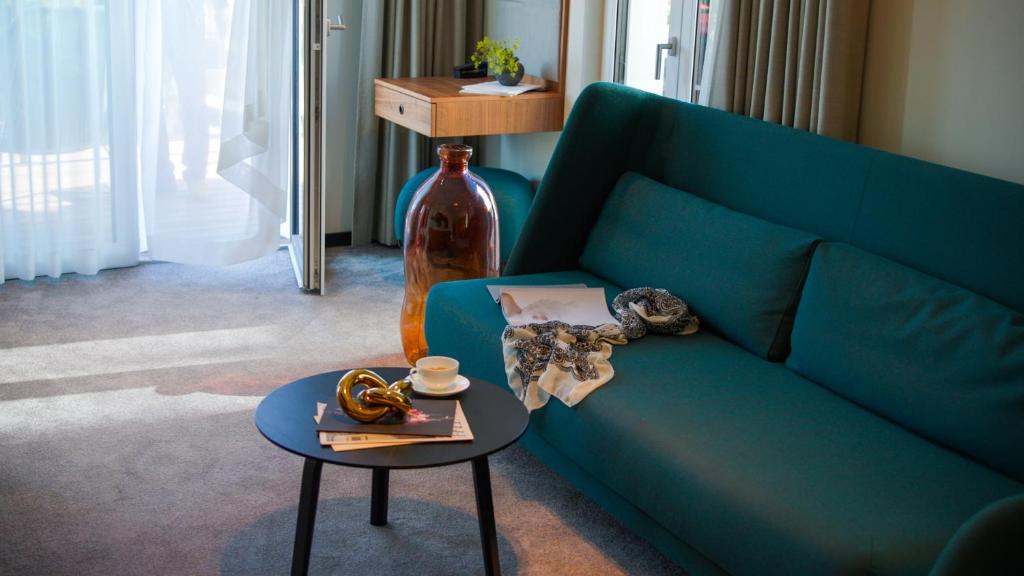 ein Wohnzimmer mit einer blauen Couch und einem Tisch in der Unterkunft Baltic Hideaways Beach Hotel Warnemünde in Warnemünde