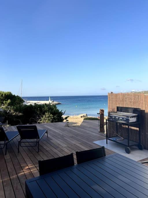 une terrasse avec un barbecue, une table et des chaises et l'océan dans l'établissement Maison en bord de mer, à Lumio
