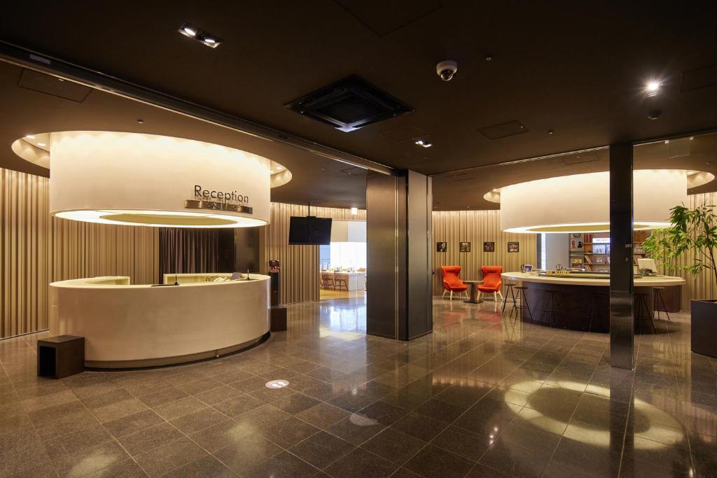 a lobby of a hotel with two lights and a counter at Kobe Motomachi Tokyu REI Hotel in Kobe