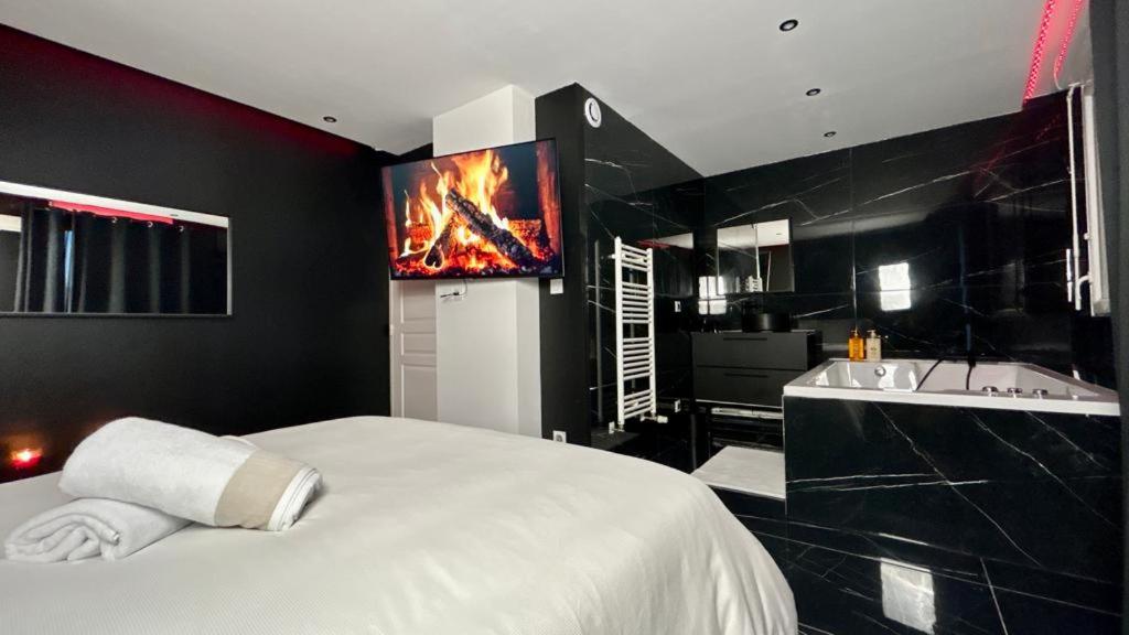 Un dormitorio con una cama y un televisor en la pared. en Black Room: Votre Love Room près de Lyon, en Vénissieux