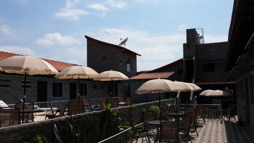 eine Terrasse mit Tischen, Stühlen und Sonnenschirmen in der Unterkunft Forte Do Pouso Hospedagens in Saquarema