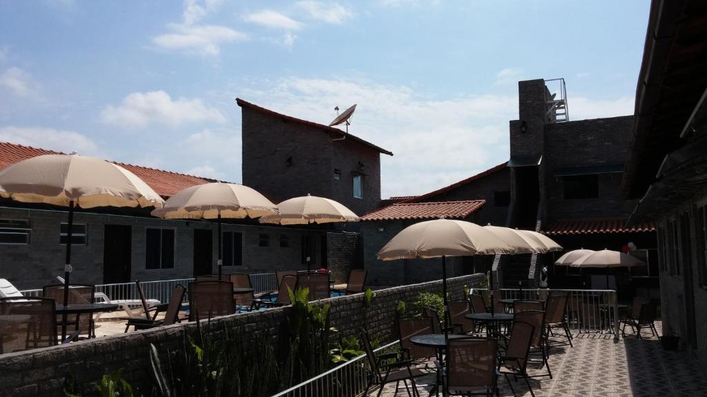 a patio with tables and chairs with umbrellas at Forte Do Pouso Hospedagens in Saquarema