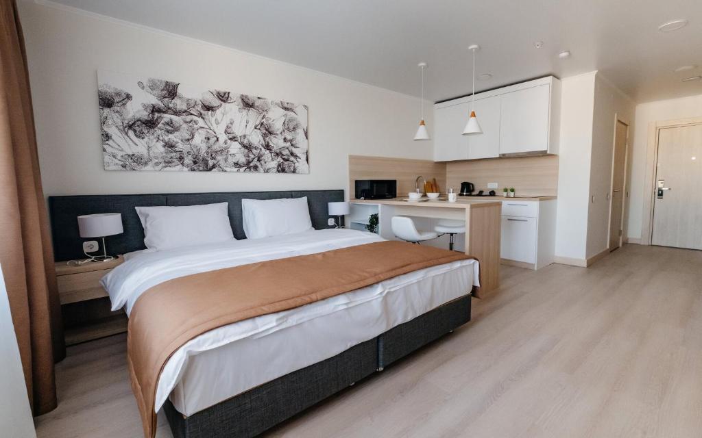 Un dormitorio con una cama y un escritorio y una cocina. en Yes Botanical Apartments, en Astana