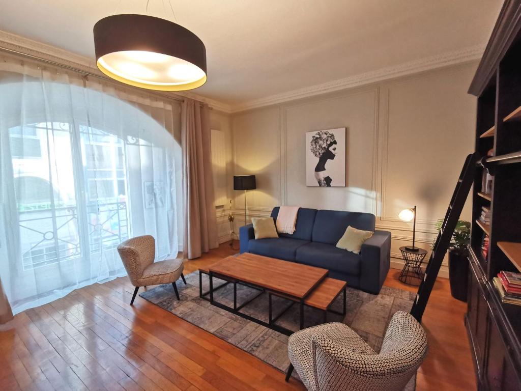 a living room with a blue couch and a table at Le Royal Couëdic - Les Maisons de Madeleine in Nantes