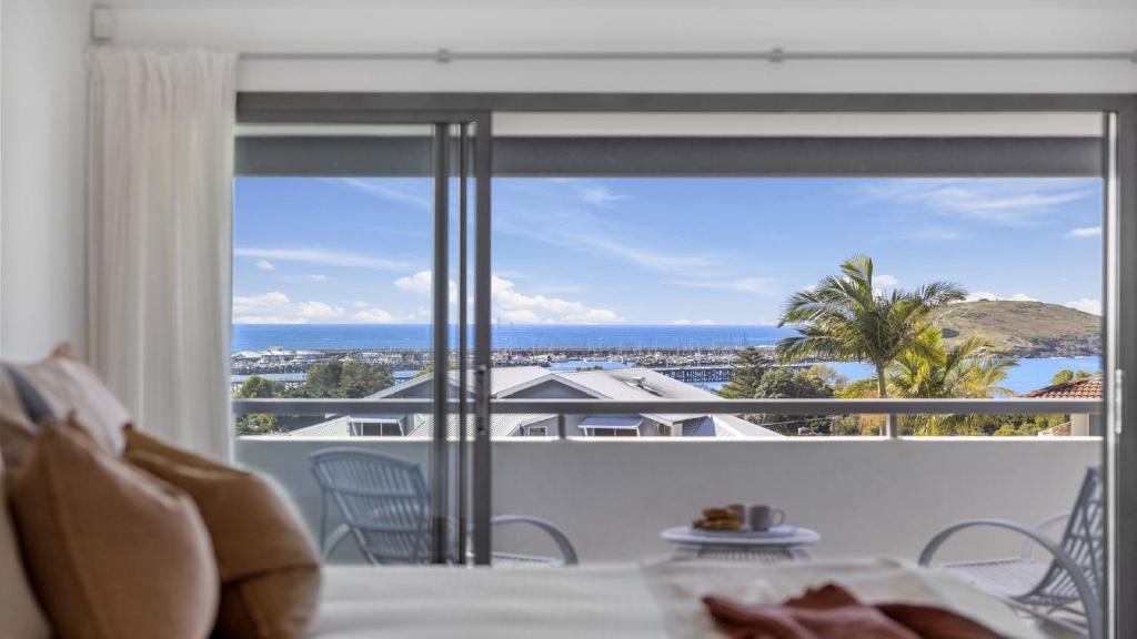 Un dormitorio con un gran ventanal con vista al mar. en Pacific Piers - Walk to Cafes, Pub & Jetty Beach, en Coffs Harbour