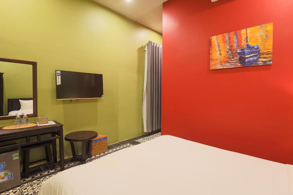 A bedroom view shows the bed facing a wall-mounted television and compact desk.