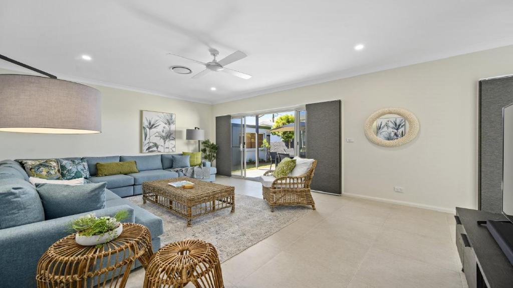 ein Wohnzimmer mit einem blauen Sofa und Stühlen in der Unterkunft Sea Pine Cottage - In the heart of Sawtell Village, Sleeps 6 in Sawtell