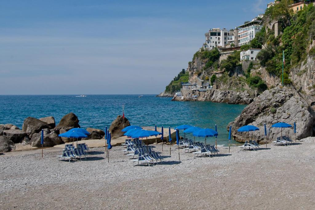 a group of blue chairs and umbrellas on a beach at Hotel Aurora in Amalfi