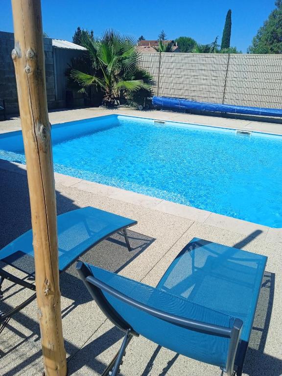 une piscine avec deux chaises et un poteau à côté dans l'établissement Charme et détente, à Allex