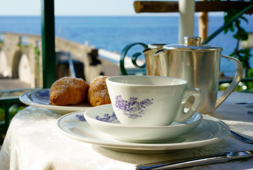 a table with two plates and a cup and croissants at Hotel Aurora in Amalfi