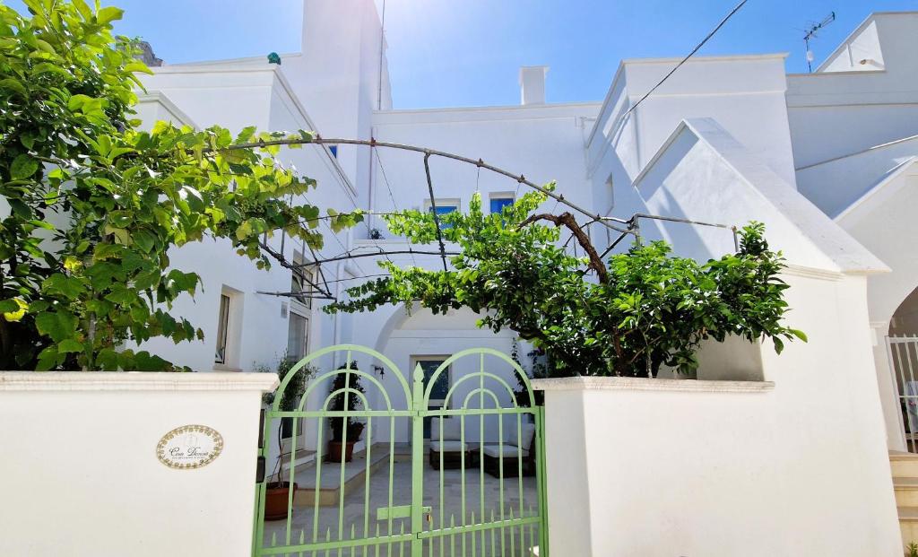 a white house with a gate and trees at Corte Dioniso Eco Apartments & Suites in Crispiano