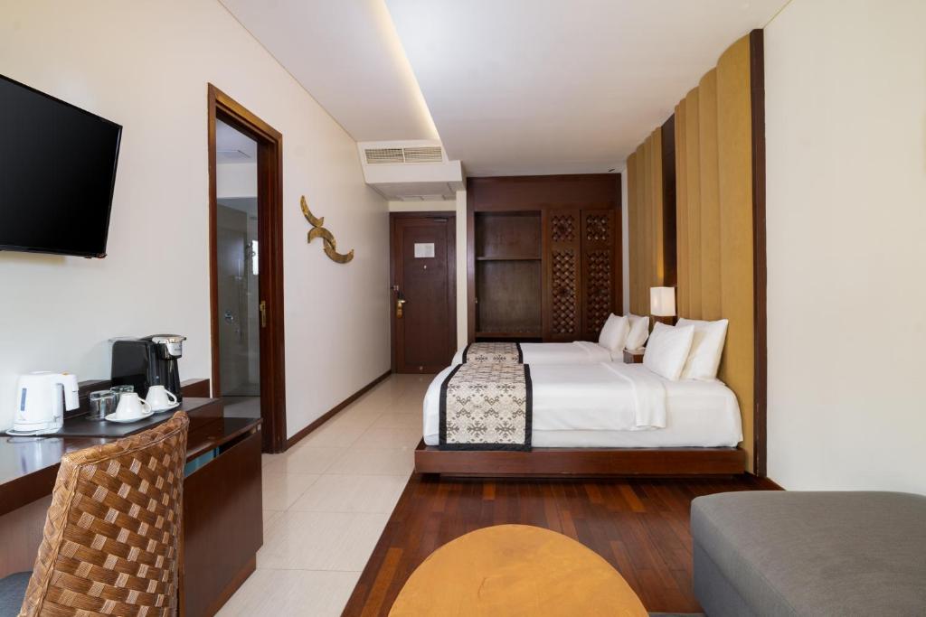 a hotel room with a bed and a television at MERUSAKA Nusa Dua in Nusa Dua