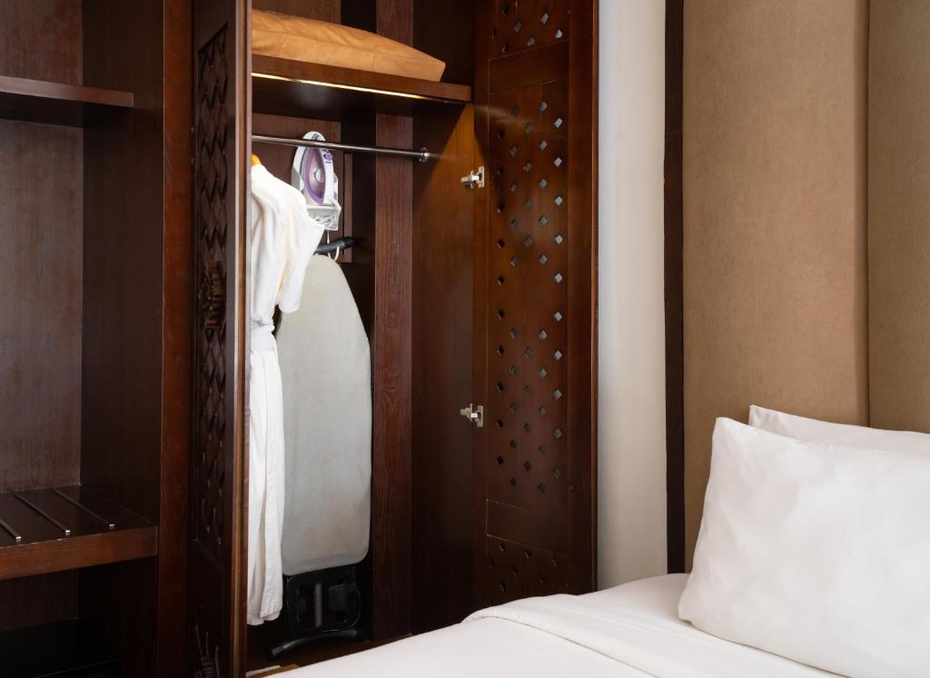 a bedroom with a bed and a wooden closet at MERUSAKA Nusa Dua in Nusa Dua