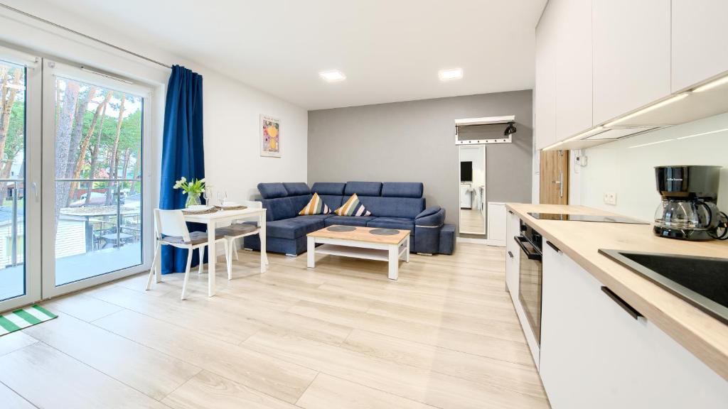 a living room with a blue couch and a kitchen at Horizon Park II, Sun & Snow in Dziwnówek