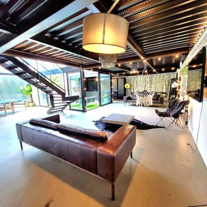 un grand salon avec un canapé brun et une table dans l'établissement Loft élégant,spacieux,atypique, à Colombes