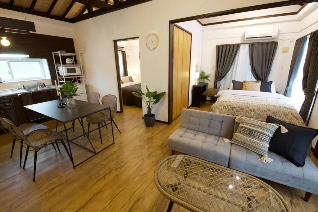 a bedroom with a bed and a table and a kitchen at Junglia Okinawa 崎本部戸建プール付き f in Motobu