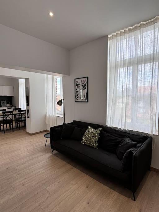 - un canapé noir dans le salon avec une table dans l'établissement Duplex neuf à 15 min de LILLE, à Noyelles-lès-Seclin