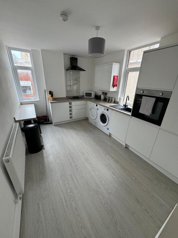 a large white kitchen with a washing machine in it at Theo apartment 150 meters from the winter gardens large groups welcome in Blackpool