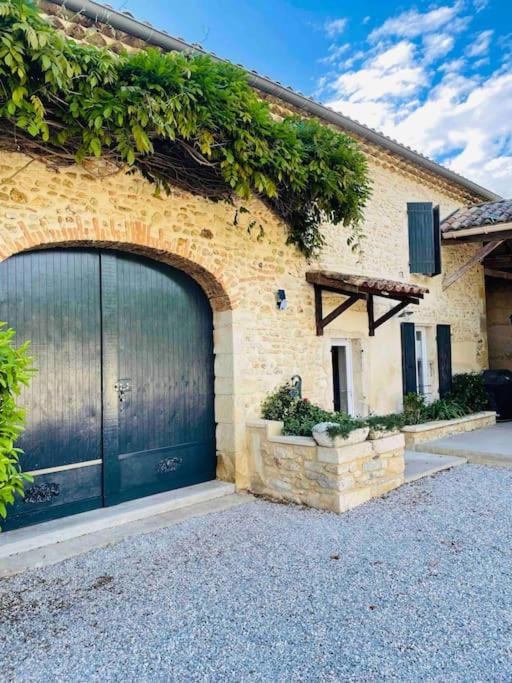 un bâtiment en briques avec une porte de garage et des vignes dans l'établissement Aaaaa, à Montboucher-sur-Jabron