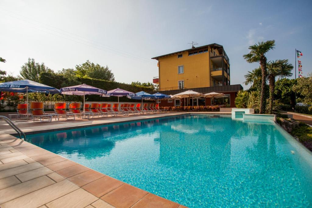 a swimming pool with chairs and a building in the background at Hotel San Vito in Bardolino