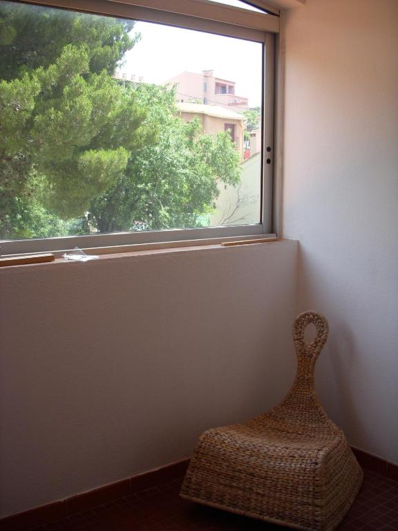 une chaise en rotin assise devant une fenêtre dans l'établissement Collioure Appartement proche de la mer, à Collioure