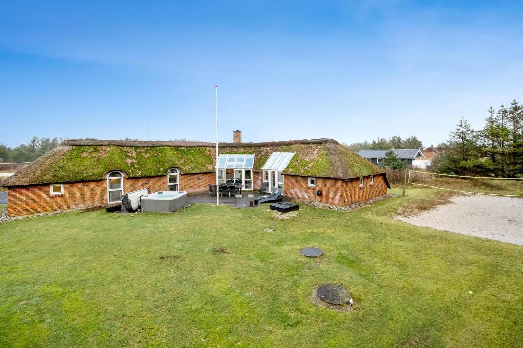 una vieja casa de ladrillo con un techo cubierto de hiedra en Large Pool House With 6 Person Outdoor Spa 1015, en Ringkøbing