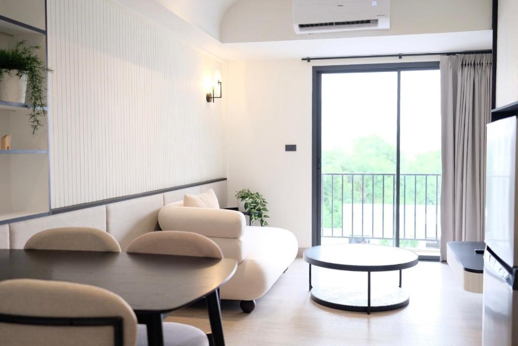 A bright sitting area with a sofa, dining table and balcony doors.