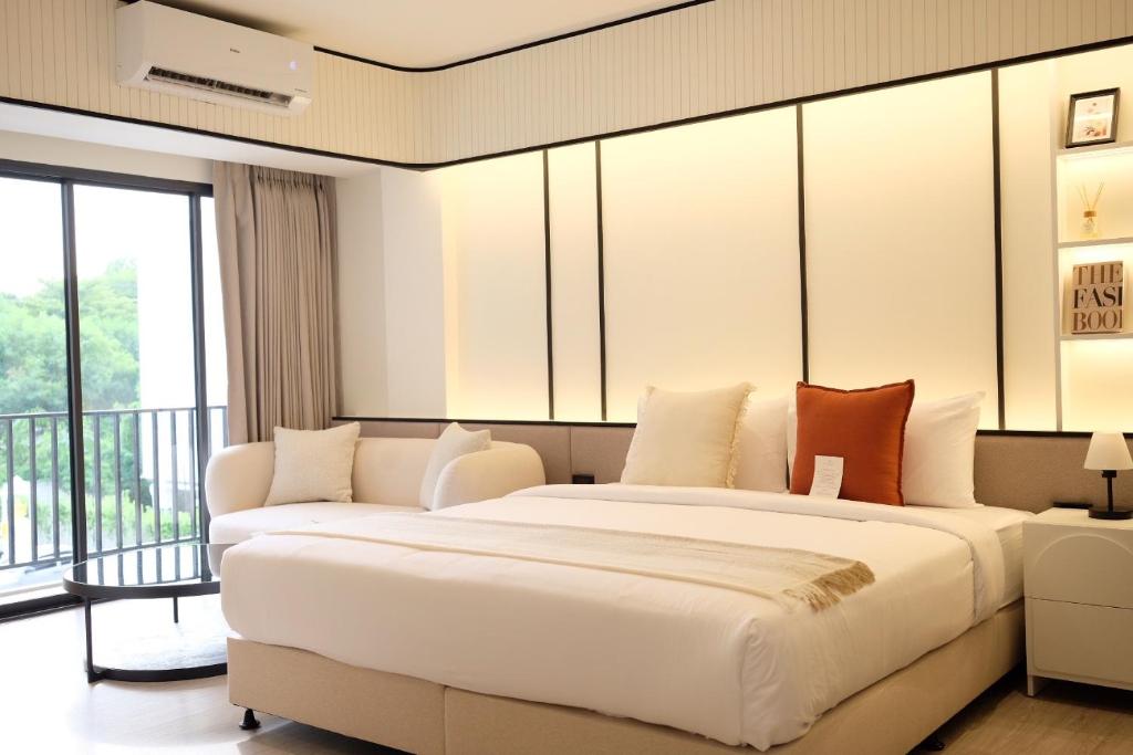 A styled bedroom with a large bed, sofa, balcony doors and reading light.