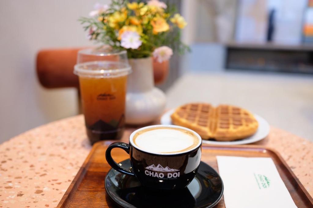 A styled breakfast tray with coffee, iced tea, a waffle and flowers.
