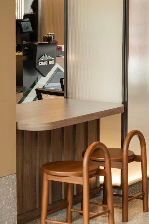 A narrow wooden work counter with two stools beside a coffee station.