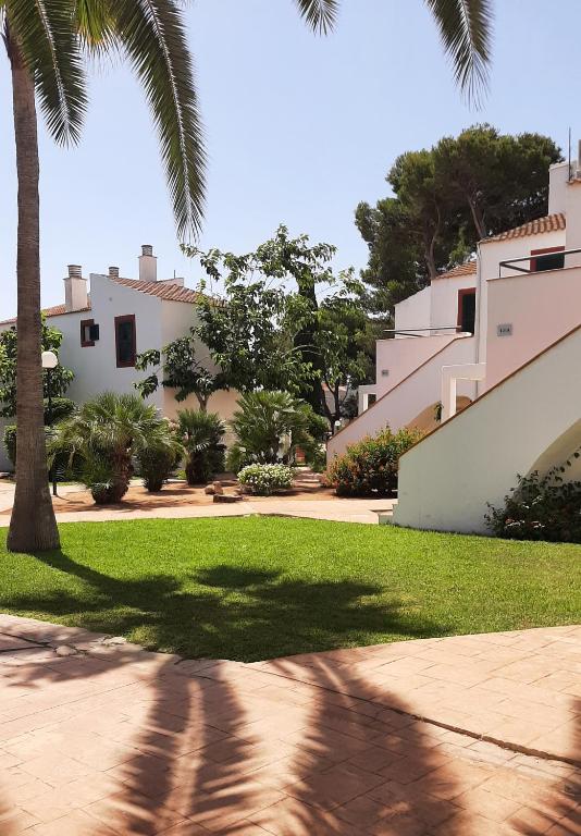 a shadow of a palm tree on a sidewalk in front of a house at Aparthotel FLORA PARK & AQUAROCK in Cala en Bosc