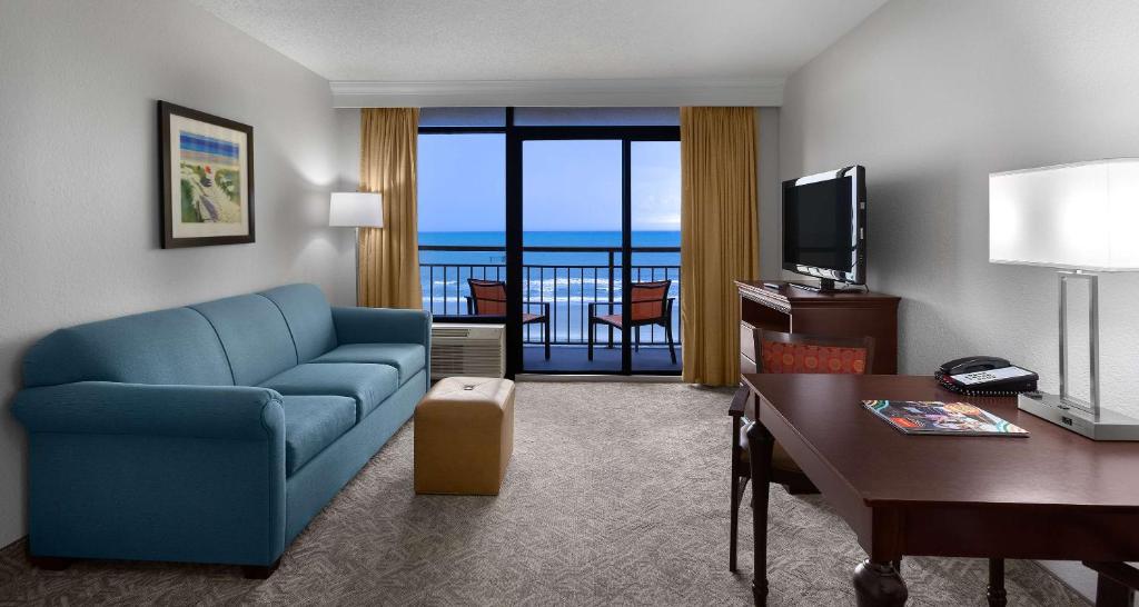 a living room with a blue couch and a television at Best Western Ocean Sands Beach Resort in Myrtle Beach