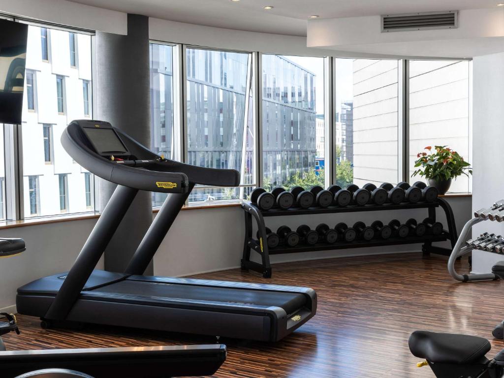 a gym with a treadmill in a room with windows at Sofitel Luxembourg Europe in Luxembourg