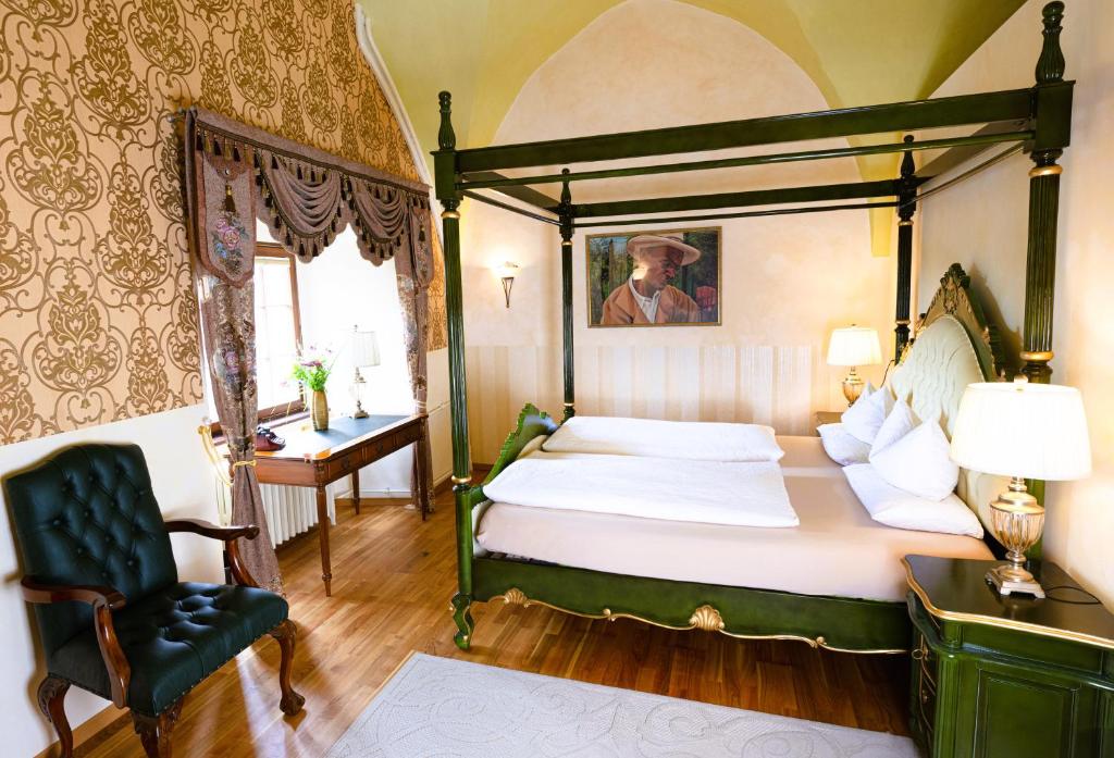 a bedroom with a four poster bed and a chair at Hotel & Tagungszentrum Schloss Hohenfels in Hohenfels
