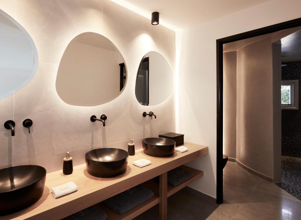 two sinks in a bathroom with two mirrors at Kalisti Hotel & Suites in Fira