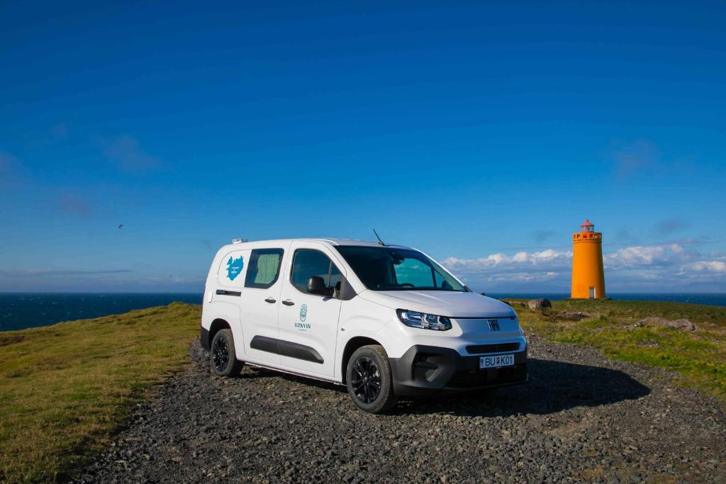 un furgone bianco parcheggiato di fronte a un faro. di FIAT Doblo Maxi Camper Basic a Ytri-Njarðvík